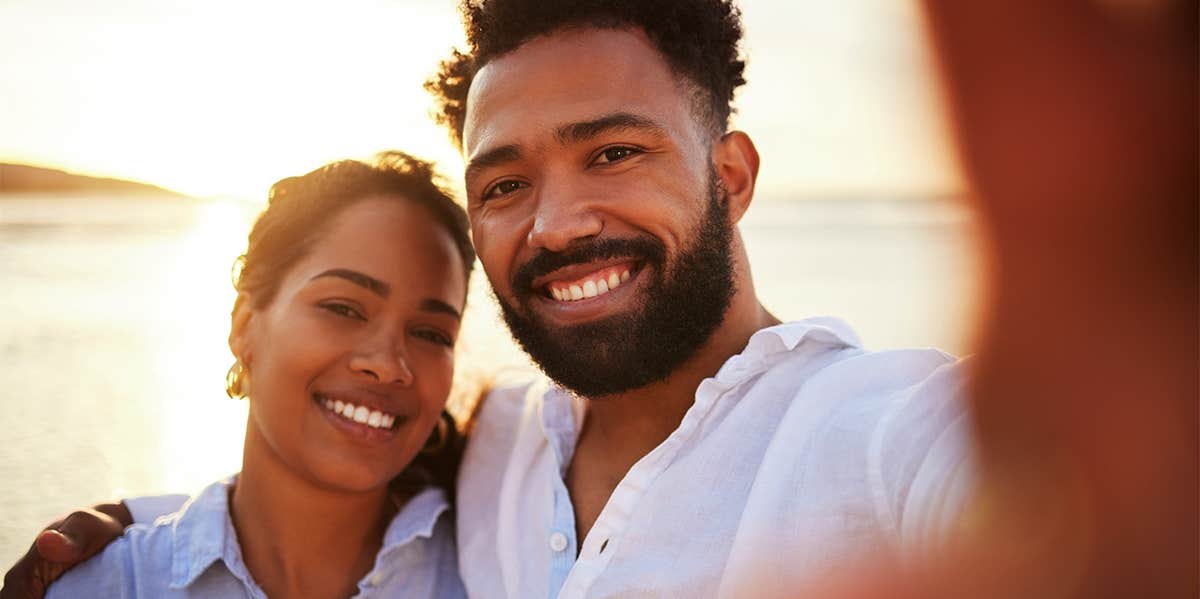 smiling couple taking selfie on the beach