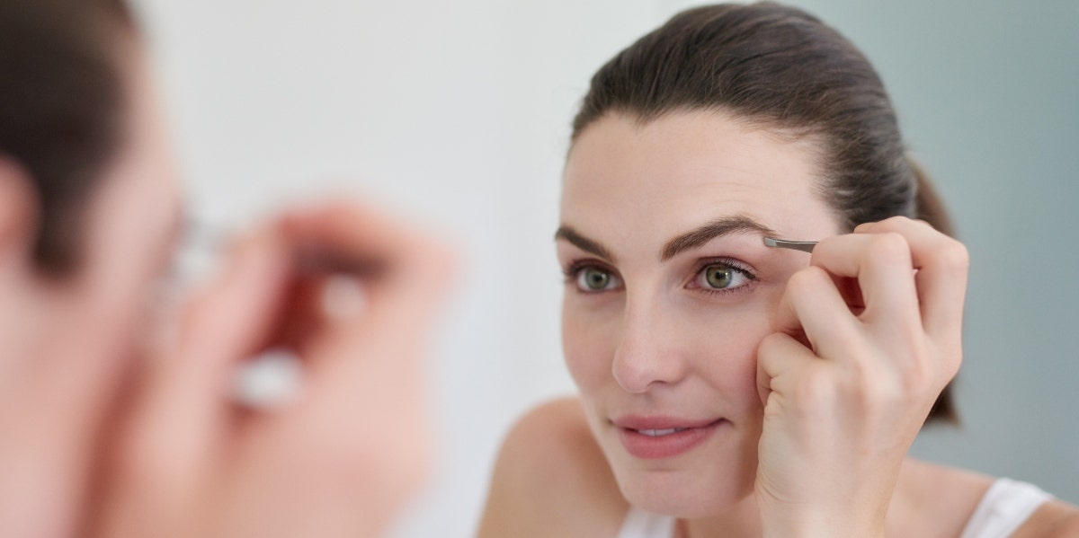 woman doing eyebrows in the mirror