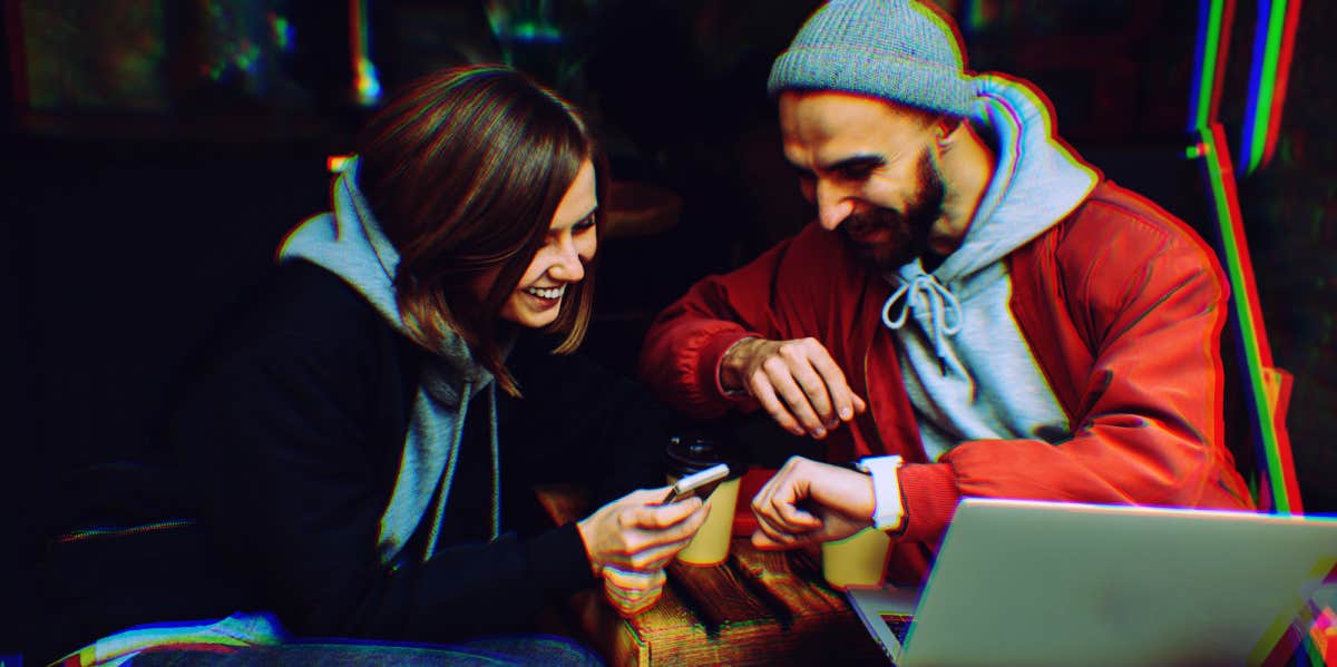 man and woman looking at their devices noticing synchronicities