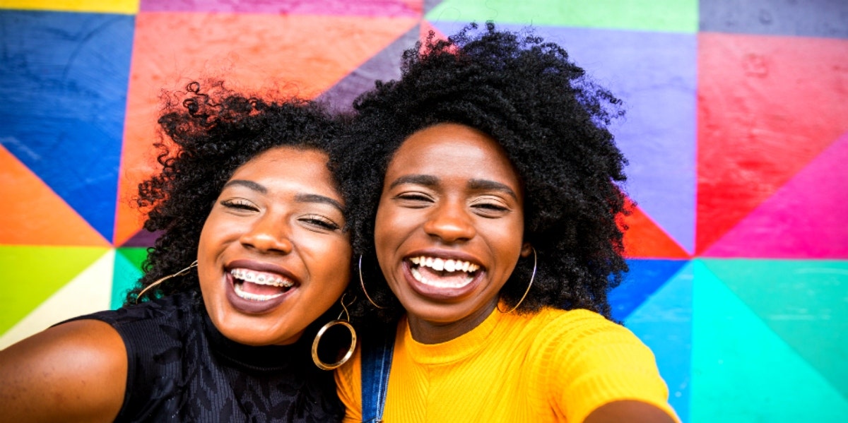 two Black women smiling on a bright background