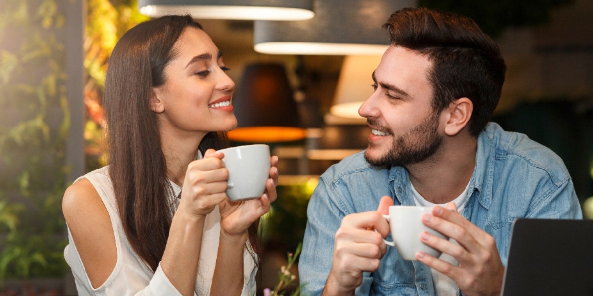 man and woman smiling at each other over coffee