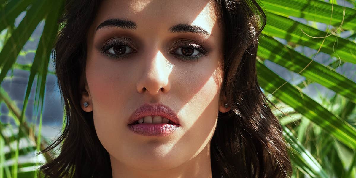 What Your Breakup Style Really Says About Your Personality woman frowning in front of palm leaves
