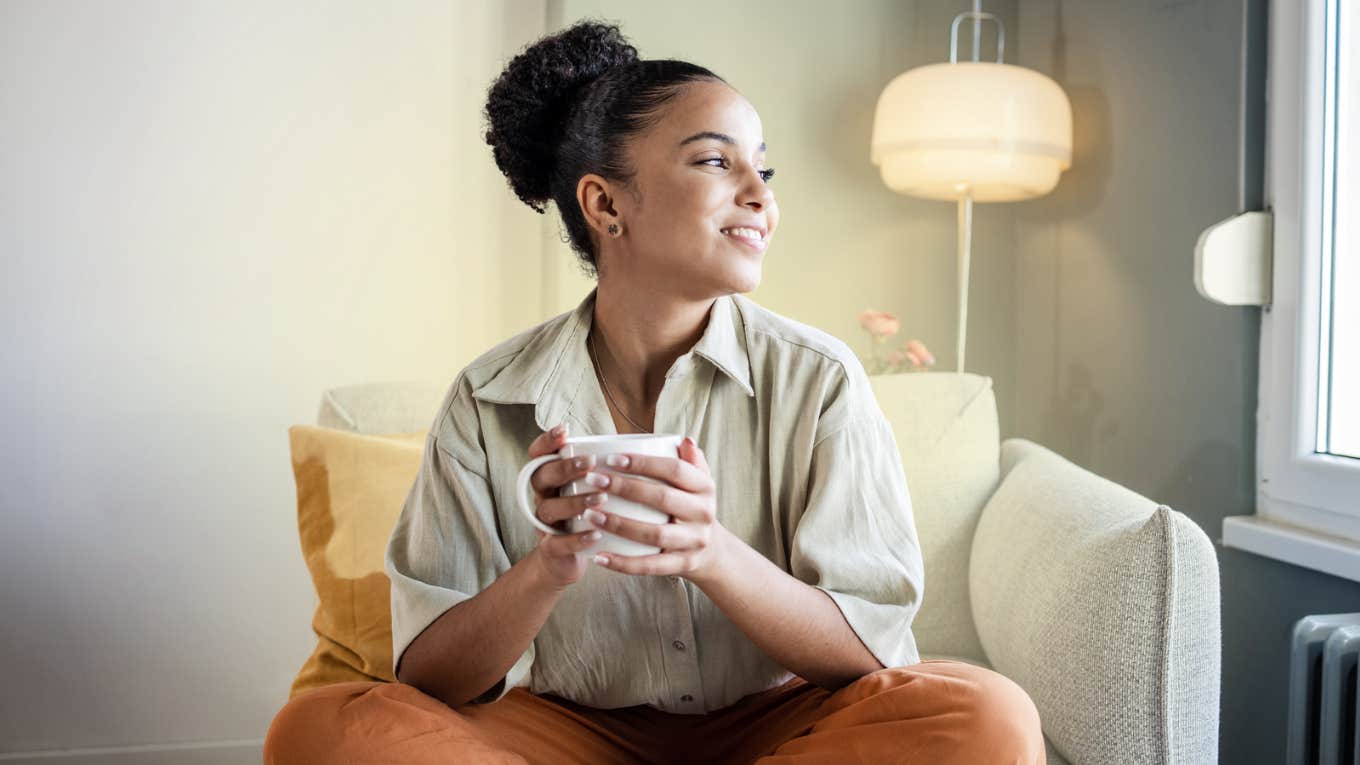 The Actual, True End Goal Of Self-Care, According To Experts Woman drinking coffee staring out