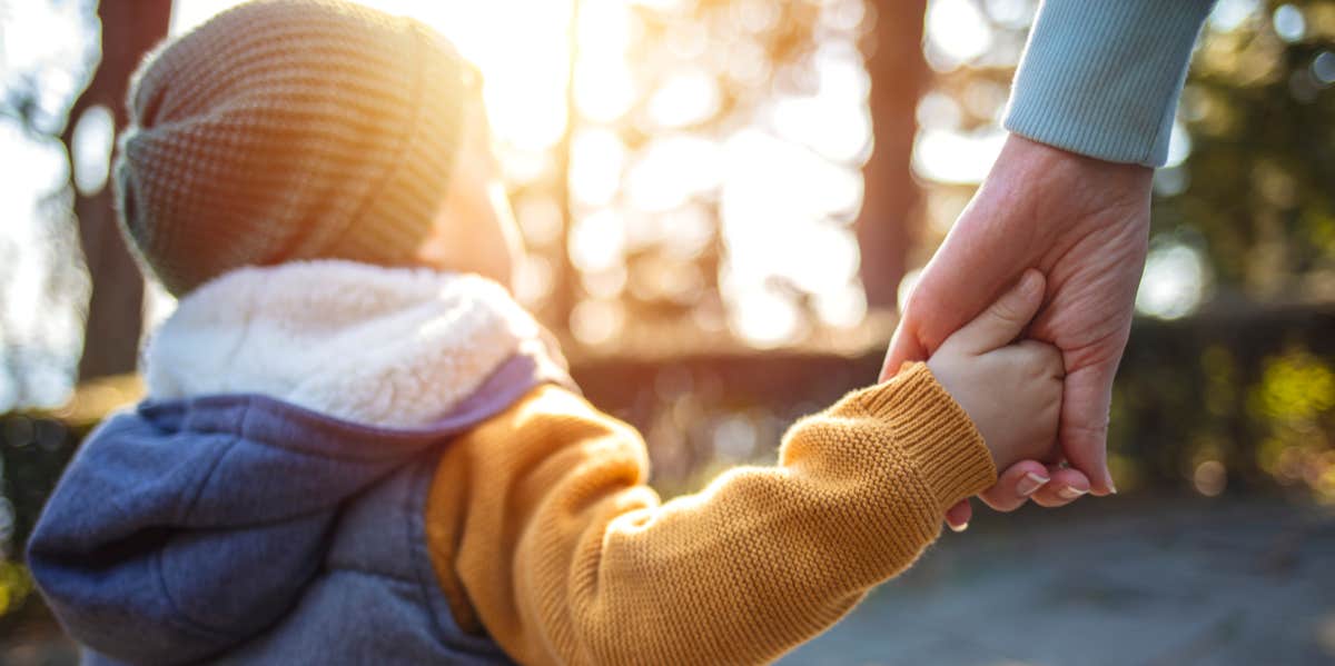 woman holding child's hand