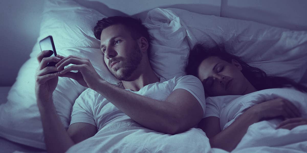 man looking at phone while on bed