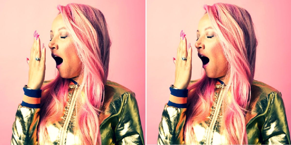 woman with pink hair and nails yawning