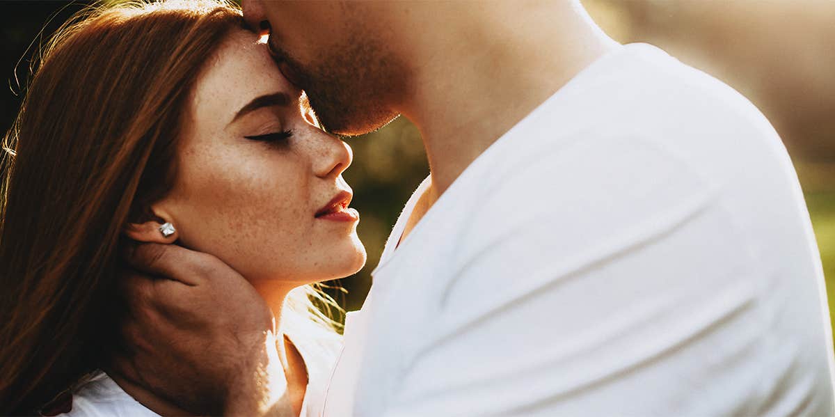 man kissing woman's forehead