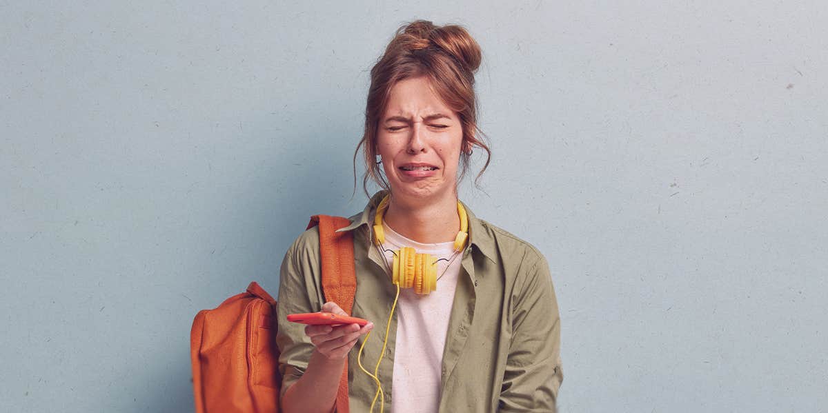 girl crying, looking at her phone