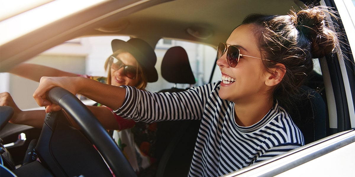 women driving in car smiling sunglasses