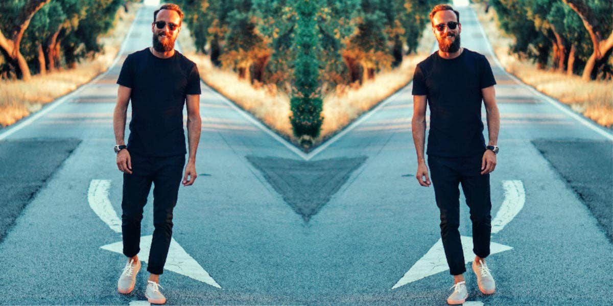 mirrored image of smiling man walking on a street toward the camera