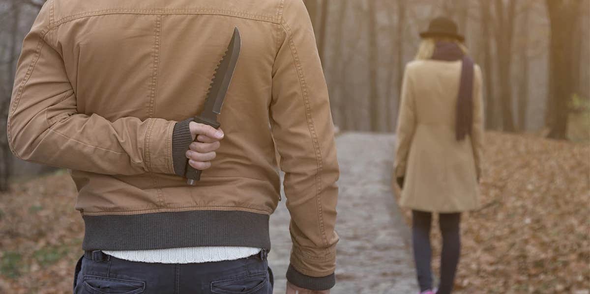 man standing behind woman with knife behind his back