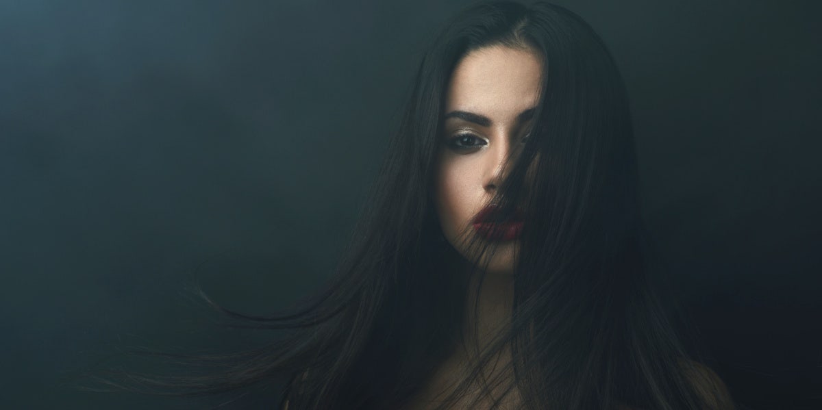 The Moment Society Taught Me What It Means To Be A Woman sad woman in the dark with hair covering face