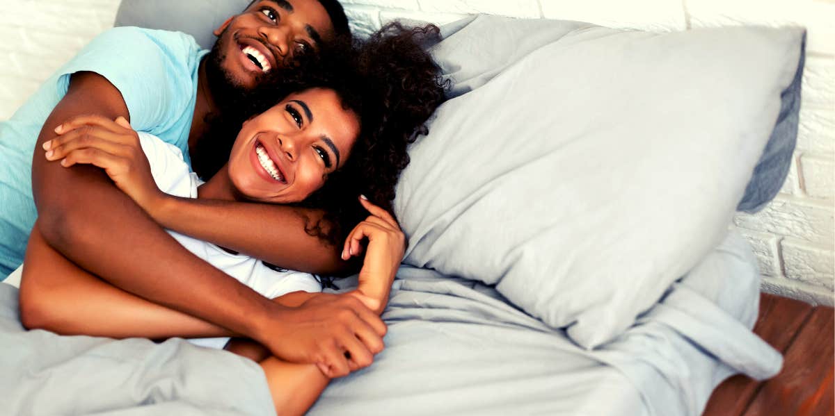 Man embracing woman in bed happily