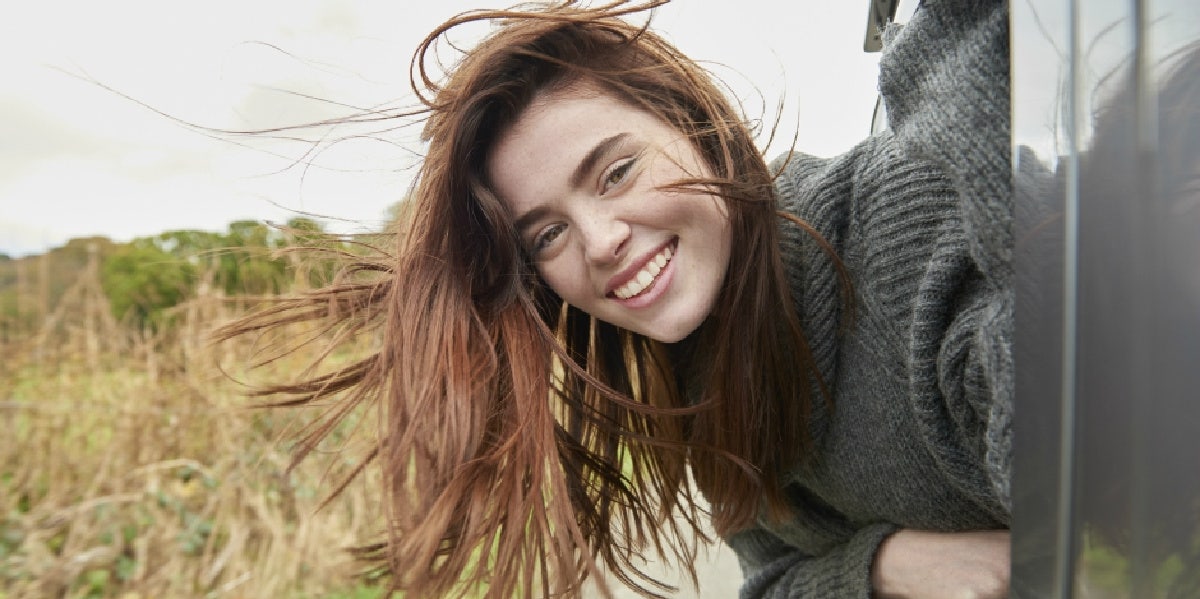 5 Weird Things Men Want In A Woman, According To Science woman looking out window smiling