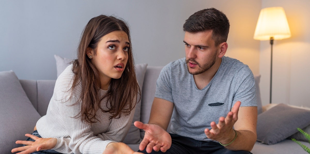 man and woman sitting on couch arguing