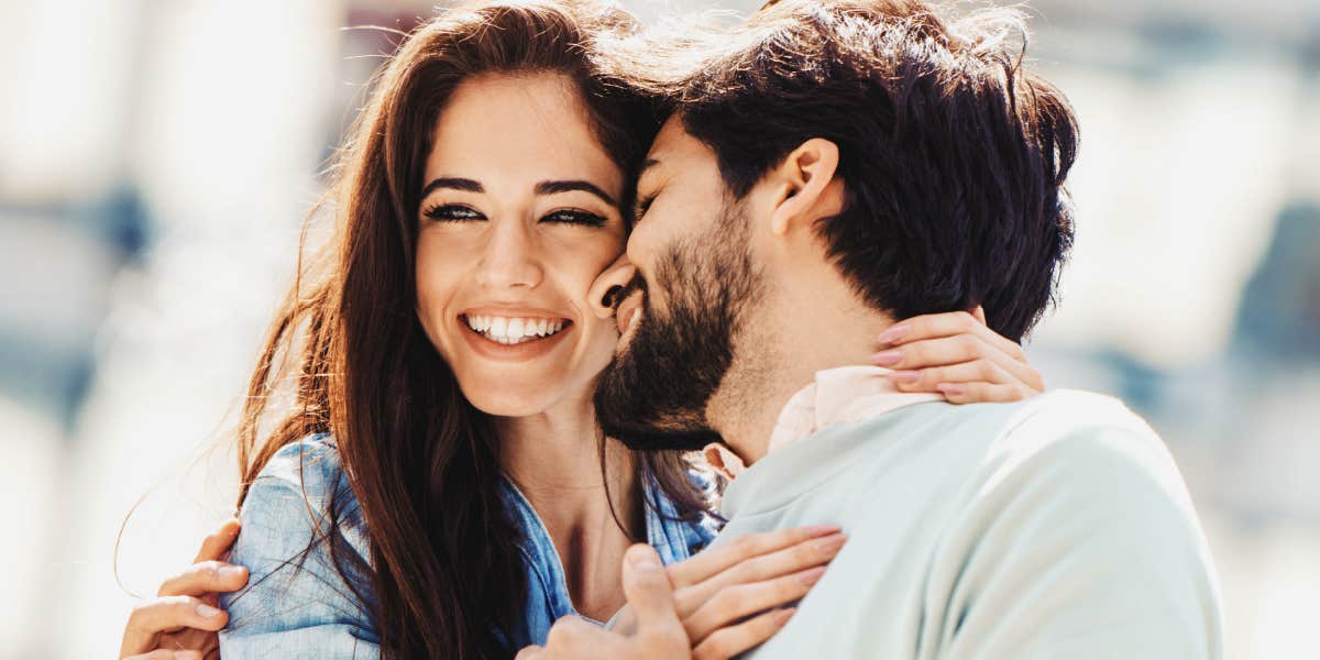 brunette wife smiling as bearded husband kisses her cheek