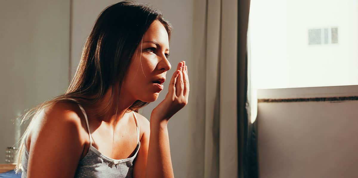 What Your Breath Is Trying To Tell You About Your Health woman smelling her breath