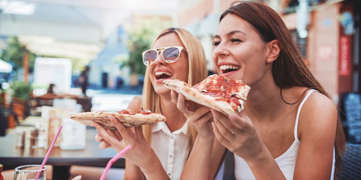 women smiling eating pizza