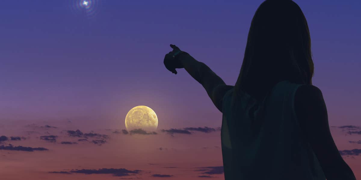What Each Zodiac Sign Can Specifically Manifest On October 14, 2023, During The New Moon Solar Eclipse In Libra woman pointing toward the moon
