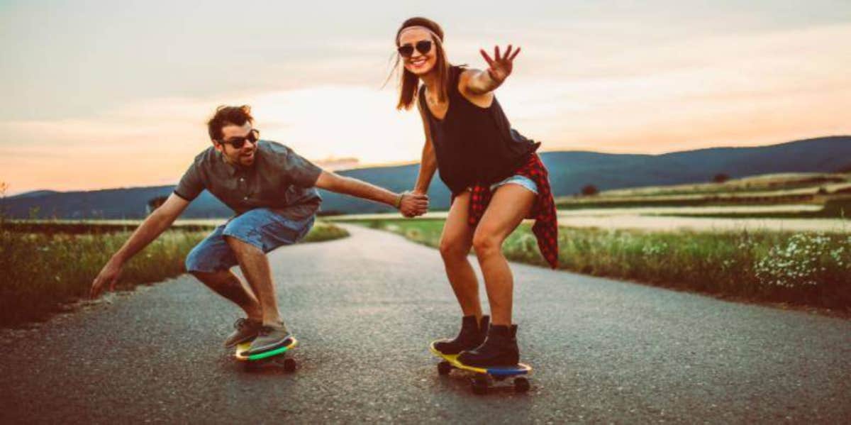 man and woman holding hands while skateboarding