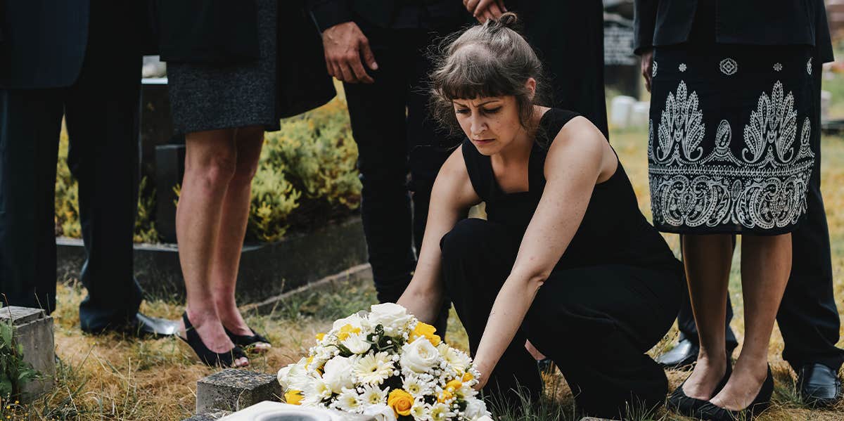 woman putting flowers on grave