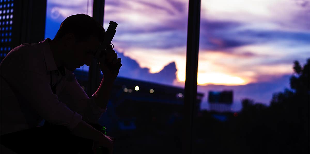 silhouette of man in room holding gun