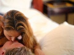 caucasian couple kissing in bed with bedroom out of focus