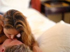 7 Ways To Set The Mood For Great Sex caucasian couple kissing in bed with bedroom out of focus
