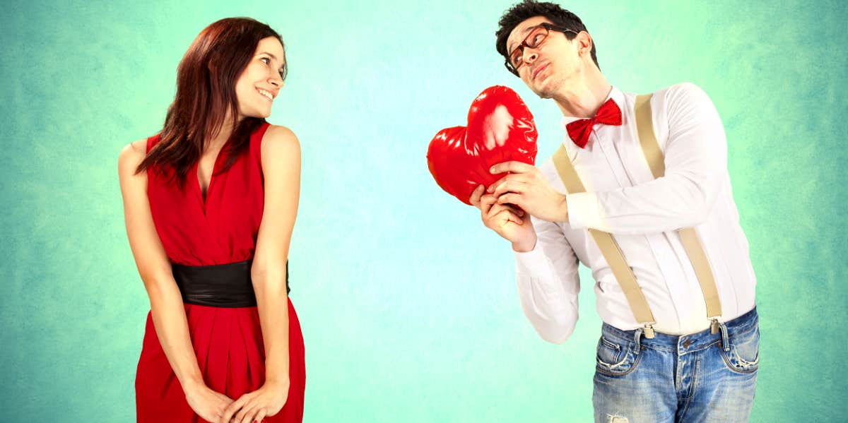cute couple man holding heart out toward woman as he's falling in love