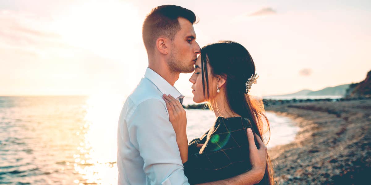 man kissing woman's forehead