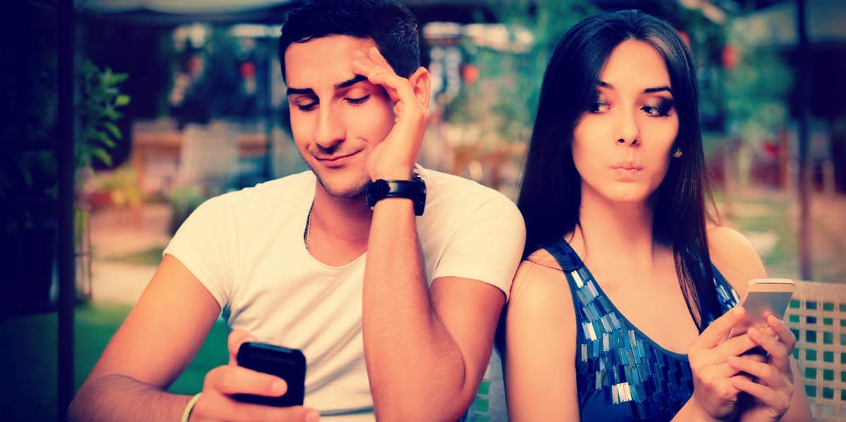Who Your Spouse Is Most Likely To Have An Affair With And Why man looking at his phone while woman looks over her shoulder to see what he is looking at