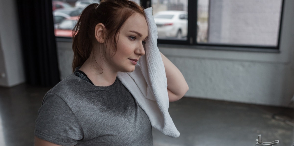 Why Am I Always Hot? 13 Common Causes & Reasons sweaty woman toweling herself off