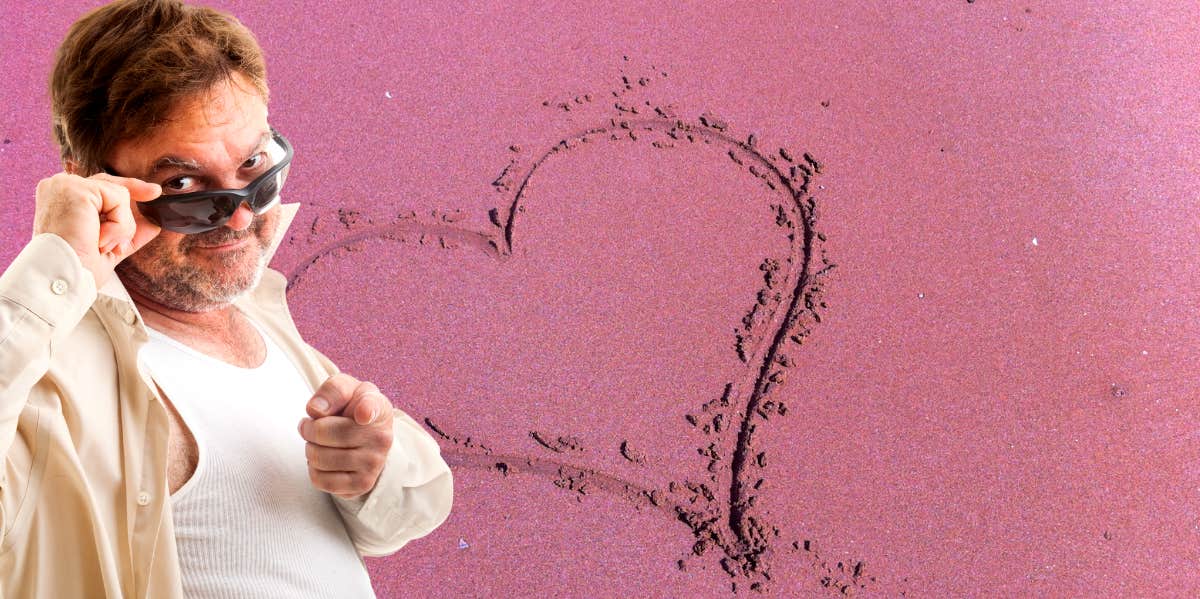 loser type guy in a white tank top pointing at the camera in front of a pink heart