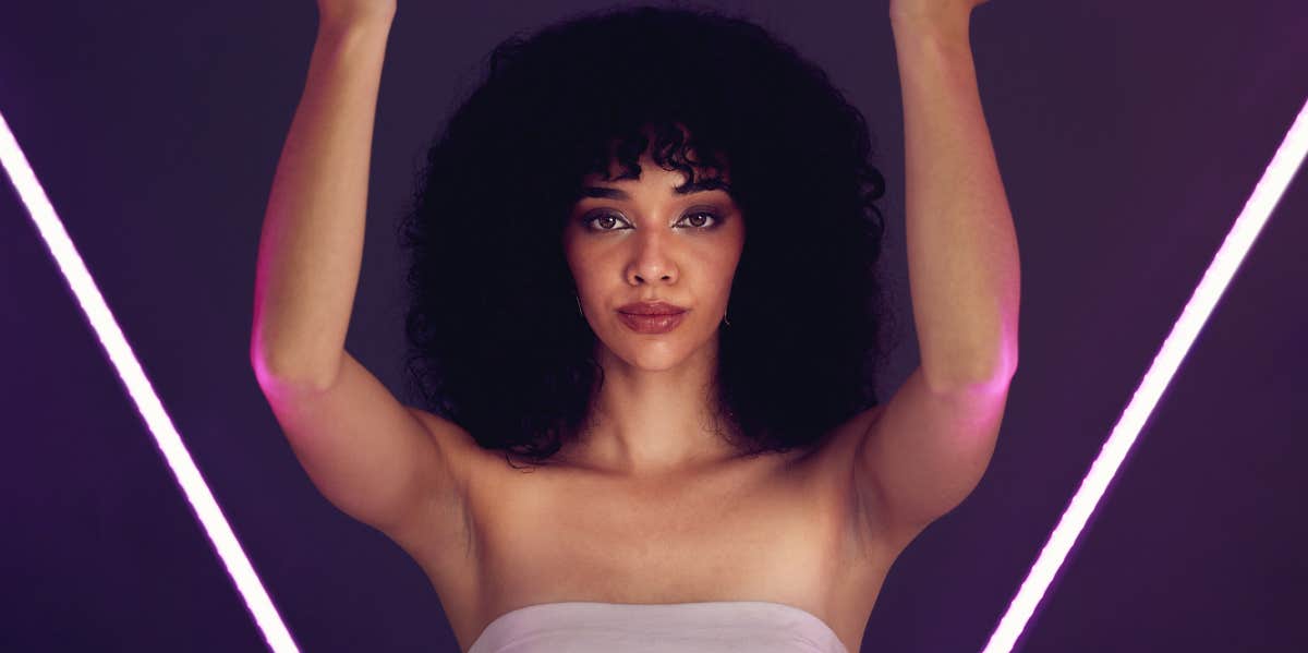 woman with afro holding a neon light