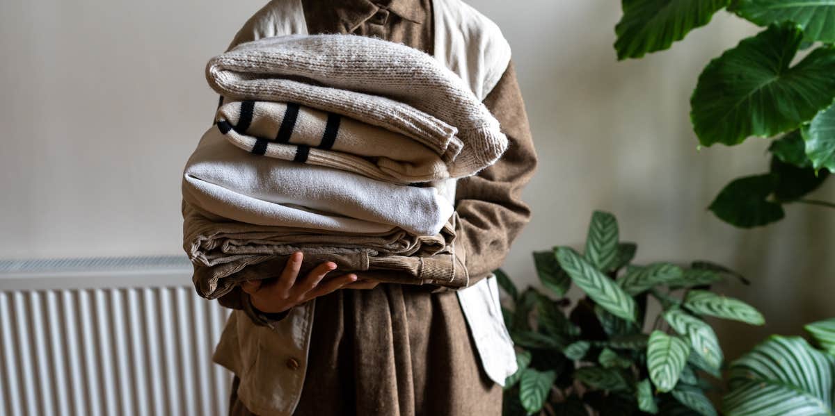 woman holding stack of clothes