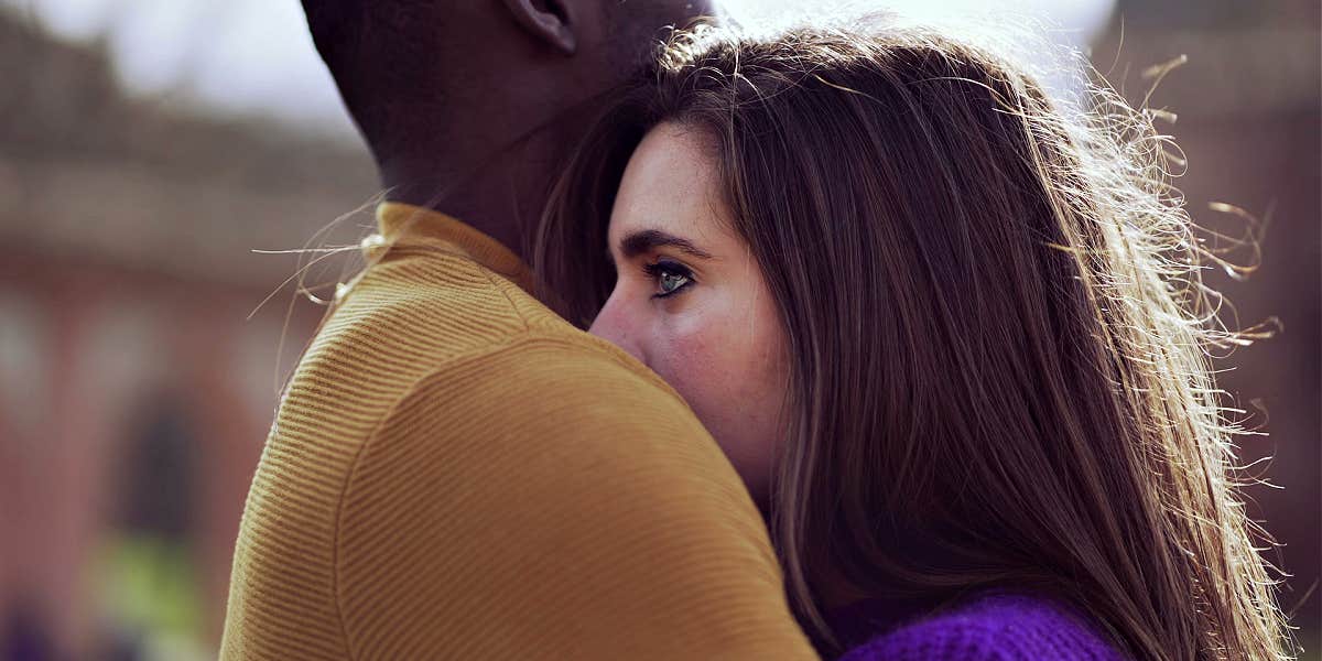 mixed race couple embracing, she looks sad, he looks away