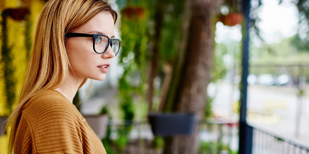 Pensive young woman looks up from book, thinking