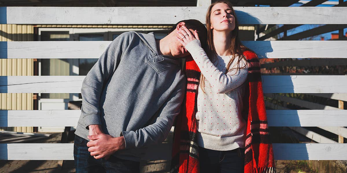 woman putting hand on man's cheek standing against gate