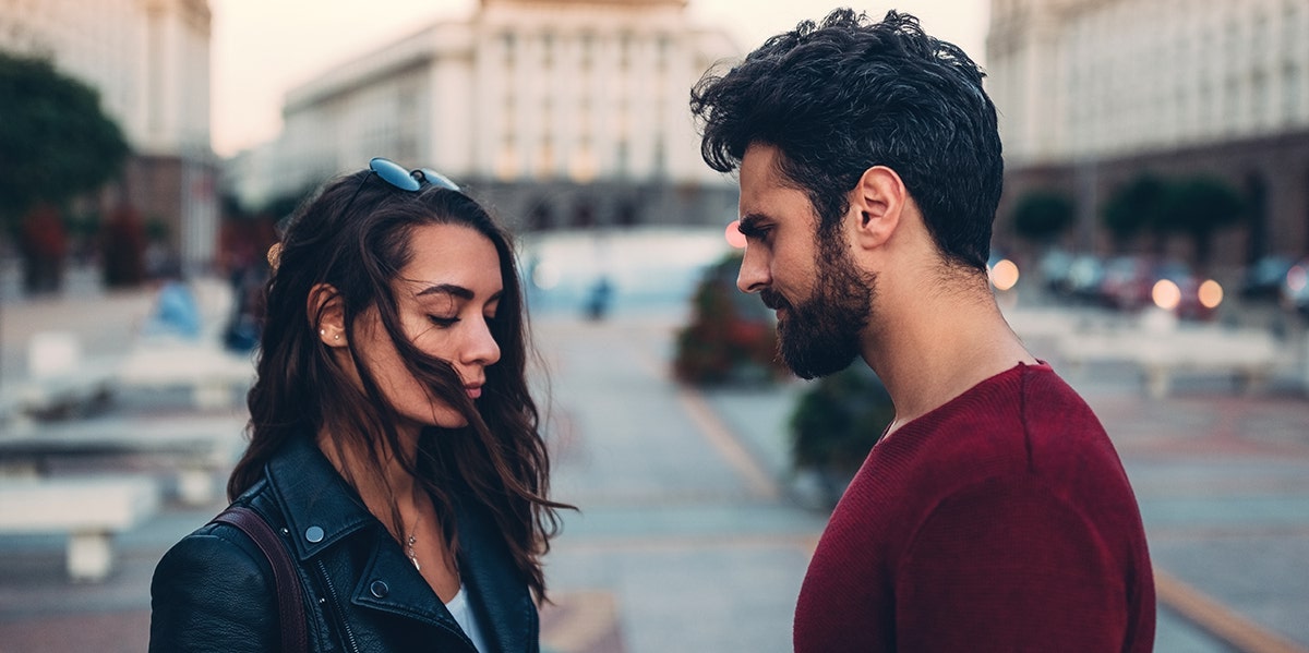 Why Do People Cheat On People They Love? couple facing each other eyes closed on busy street