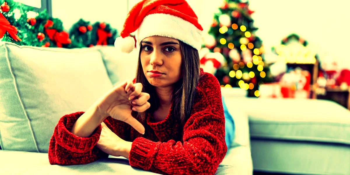 I Hate Christmas: 11 Reasons People Hate The Holidays woman with Santa hat on giving a thumbs down
