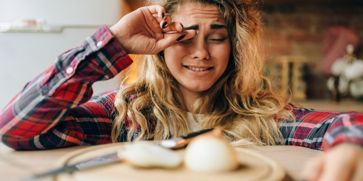 woman crying while cutting onions