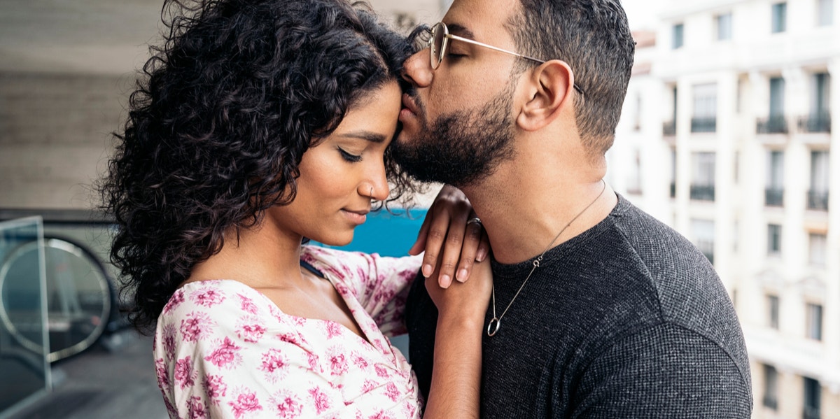 man kissing woman on forehead