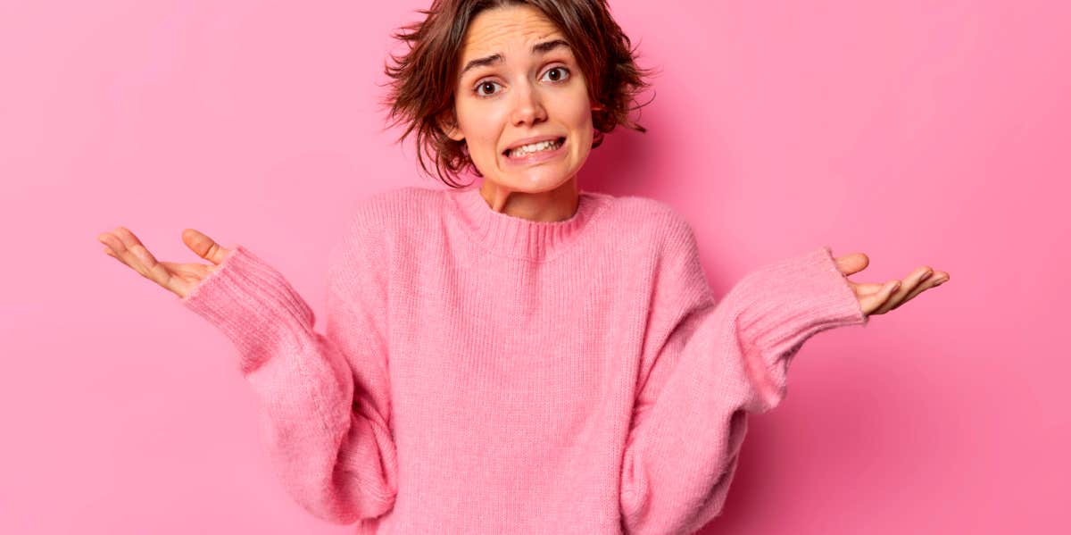 young woman in pink sweater shrugging her shoulders