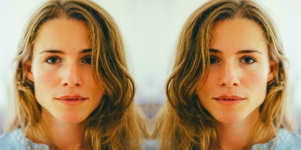 woman with long, wavy dark blonde hair looks into the camera in soft focus