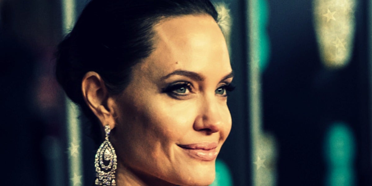 Angelina Jolie, hair pulled back in a bun, in a close-up from the right side, smiling slightly