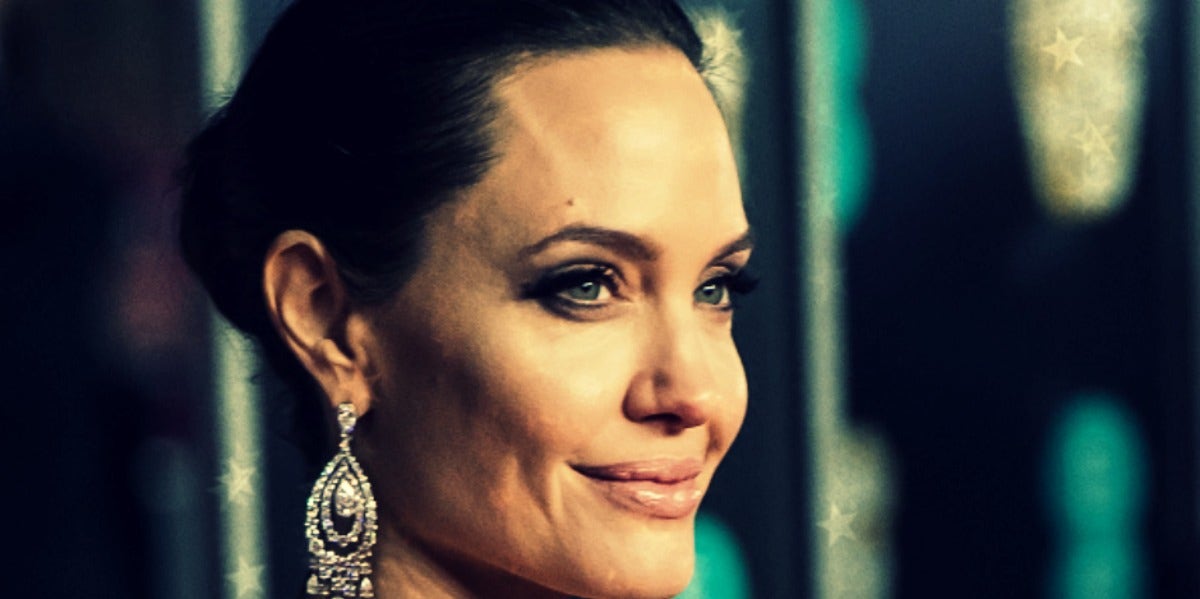 Why Are Geminis So Smart? Angelina Jolie, hair pulled back in a bun, in a close-up from the right side, smiling slightly