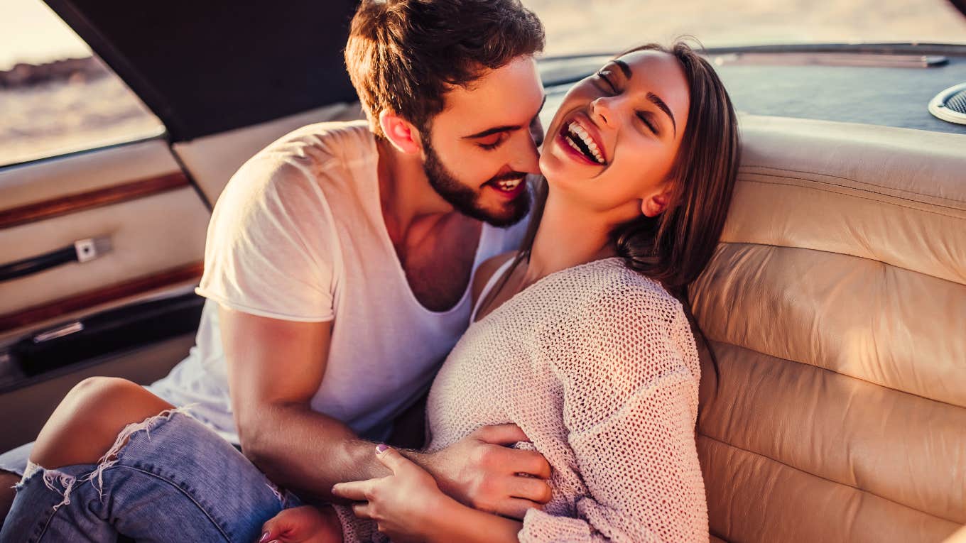 Romantic couple is sitting in green retro car on the beach