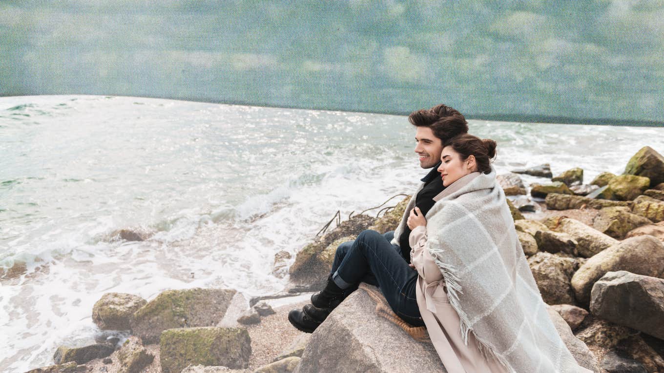 Couple snuggling under a blanket on the beach