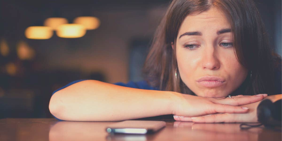 woman waiting next to her phone for a guy who is ignoring her texts