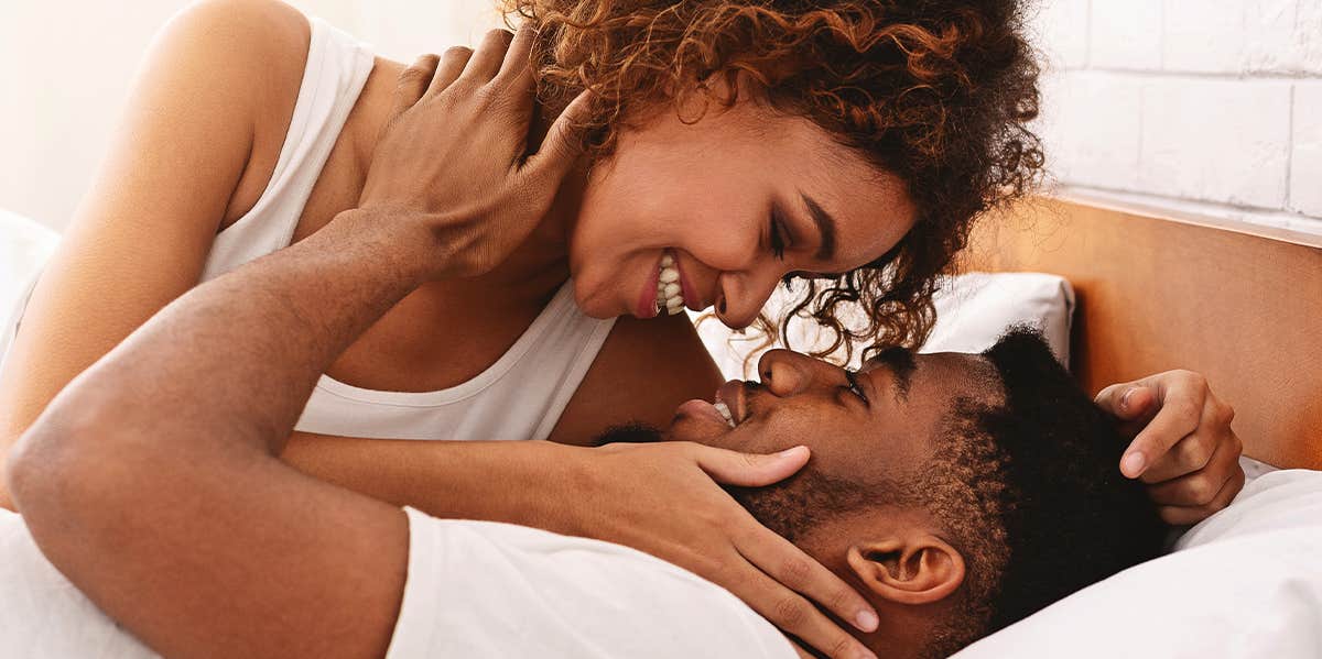 man and woman kissing in bed